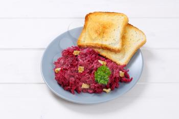plate of fresh beetroot spread with toast on white wooden background