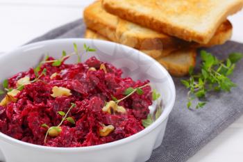 bowl of fresh beetroot spread with toast on grey place mat - close up