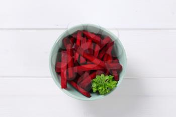 bowl of beetroot strips on white wooden background