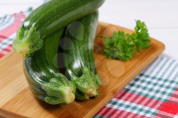 fresh green zucchini on wooden cutting board - close up
