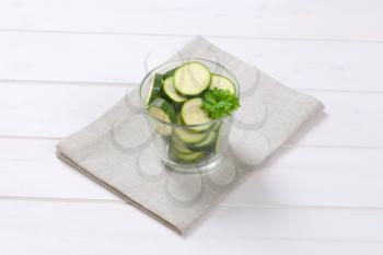 glass of green zucchini slices on beige place mat