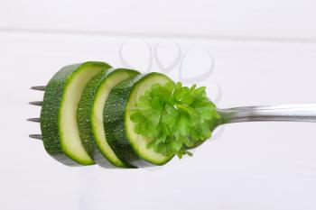 green zucchini slices impaled on metal fork
