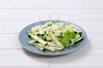 plate of zucchini strips on white wooden background