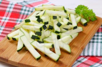 pile of zucchini strips on wooden cutting board - close up