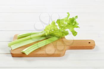stems of green celery on wooden cutting board