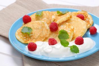 plate of american pancakes with white yogurt and fresh raspberries on beige place mat - close up