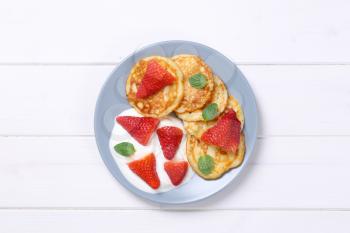 plate of american pancakes with white yogurt and fresh strawberries on white wooden background