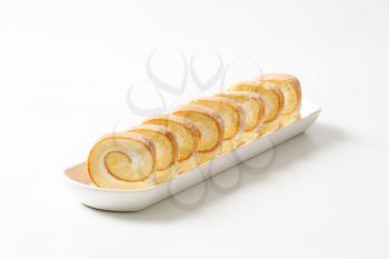 Slices of sponge cake roll with cream filling on long tray