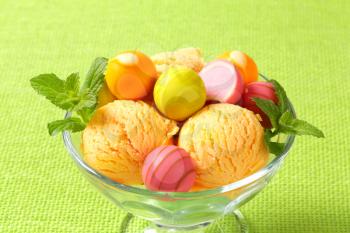 Fruit-flavored ice cream and white chocolate bonbons with fruit ganache filling on green background