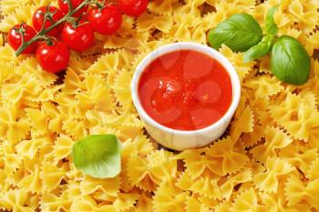Uncooked bow tie pasta with tomato sauce