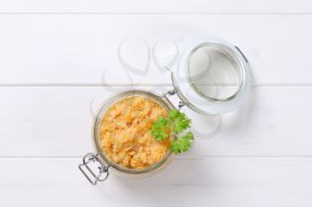 Cooked red lentils in a jar on white wooden background