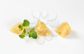 three pieces of parmesan cheese and fresh oregano on white background