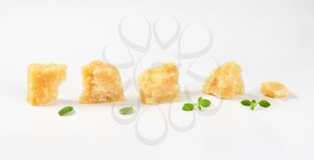 Small pieces of parmesan cheese in a row on white background