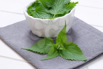 bowl of fresh nettle leaves on grey place mat - close up