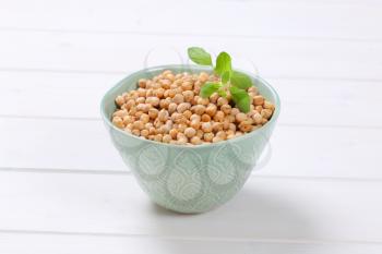 bowl of raw chickpeas on white wooden background