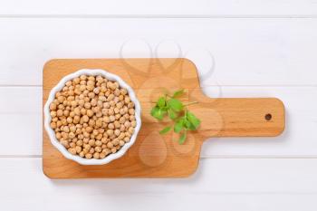 bowl of raw chickpeas on wooden cutting board