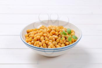 bowl of cooked chickpeas on white wooden background