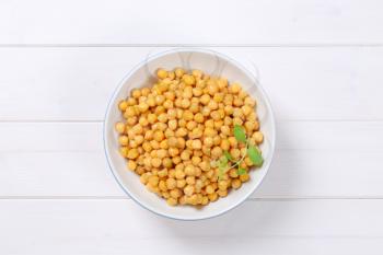 bowl of cooked chickpeas on white wooden background