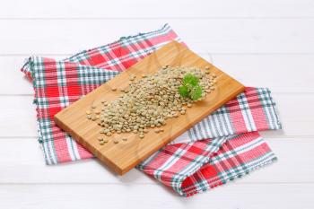 pile of dry brown lentils on wooden cutting board