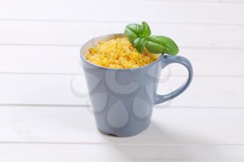 cup of small pasta shells on white wooden background