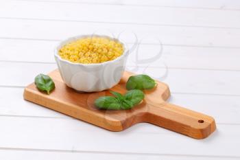 bowl of small pasta shells on wooden cutting board