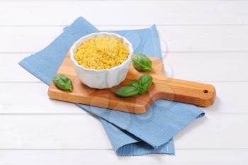 bowl of small pasta shells on wooden cutting board