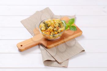 bowl of raw colored pasta on wooden cutting board