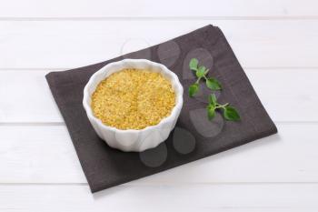 bowl of dry wheat bulgur on dark grey place mat