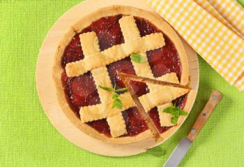 strawberry jam tart with lattice on top on wooden cutting board