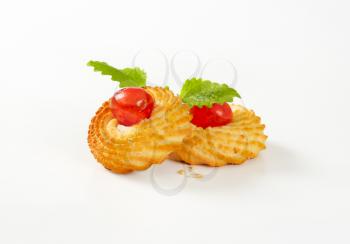 Traditional Sicilian almond cookies topped with glace cherries on white background