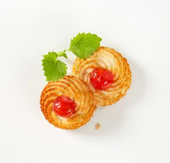 Traditional Sicilian almond cookies topped with glace cherries on white background
