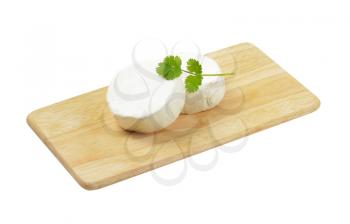 Two wheels of soft white cheese on cutting board