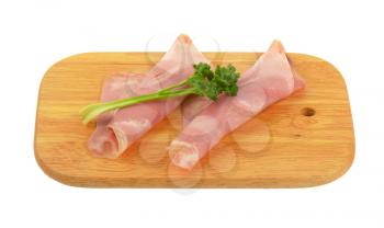 slices of pork ham with parsley on wooden cutting board