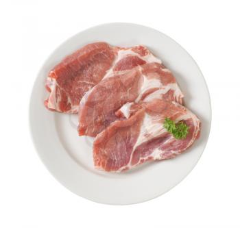 three slices of raw pork meat on white plate