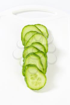 Fresh cucumber slices on white plastic cutting board