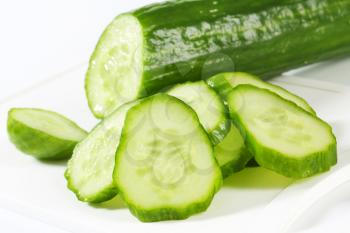 Fresh cucumber slices on white plastic cutting board