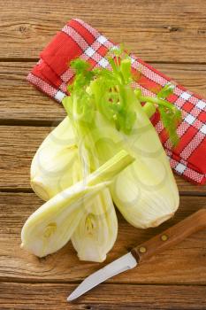 bulbs of fresh fennel and kitchen knife on wooden background