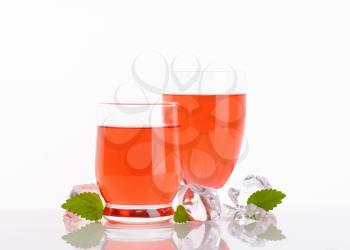two glasses of strawberry juice on white background