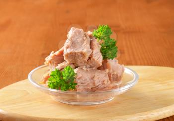 bowl of canned tuna with parsley on wooden cutting board - close up
