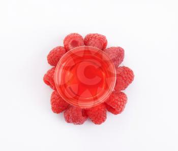 glass of raspberry juice and fresh raspberries on white background