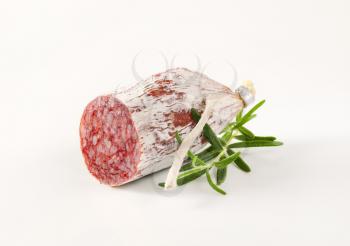 French dry cured sausage with rosemary on white background