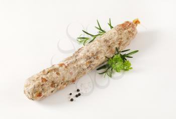 Whole dry cured sausage with spices on white background