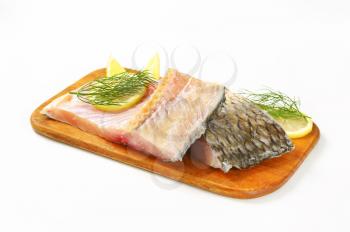 Raw carp fillets with lemon and dill on cutting board