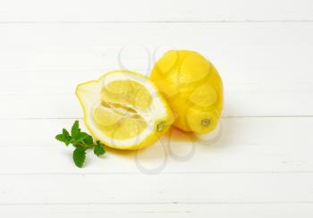 one and half lemons on white wooden cutting board