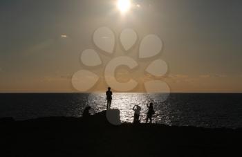 Silhouettes of four people enjoying sunset on seashore