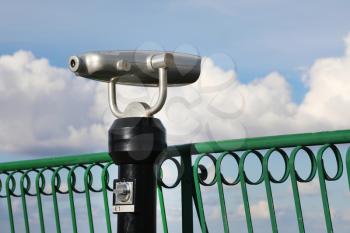 Coin-operated spy viewing machine against cloudy sky