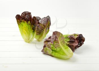 three and half heads of fresh lettuce on white wooden background