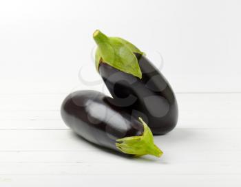 two fresh eggplants on white wooden background
