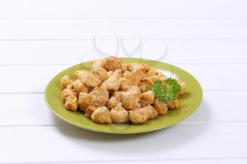 plate of soy meat cubes on white wooden background