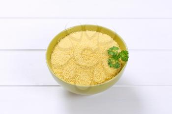 bowl of raw couscous on white wooden background